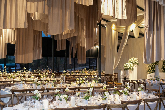 Elegant draped marquee with candlelit banquet tables
